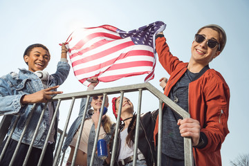 teenagers having fun and waving american flag in skateboard park, hipster style concept