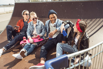 teenagers having fun in skateboard park with penny board, hipster students concept