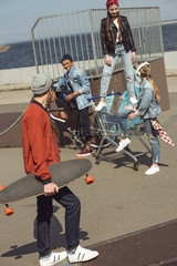 Obraz premium teenagers having fun with shopping cart in skateboard park, hipster style concept