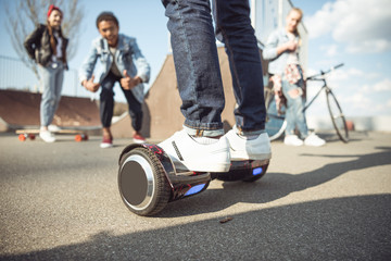 stylish hipster boy riding gyroboard with friends near by, teenagers having fun concept