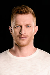 Obraz premium portrait of handsome redhead man posing and looking at camera isolated on black