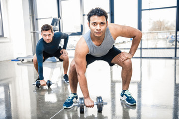 young men workout with dumbbells at gym