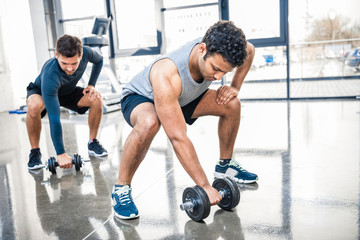 Obraz na płótnie Canvas young men workout with dumbbells at gym