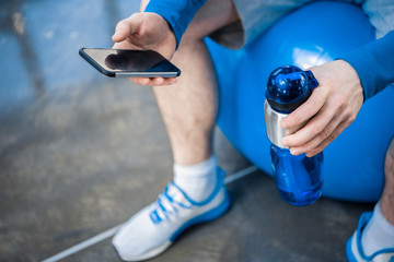 Handsome young man using smartphone at gym