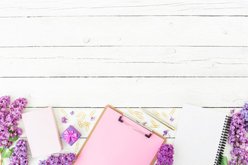 Minimalistic workspace with clipboard, notebook, pen, lilac, box and accessories on wooden background. Flat lay, top view. Beauty blog concept. Frame