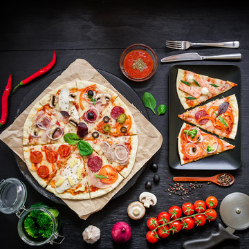 Delicious italian food. Pizza with ingredients, spices, oil and vegetables on dark background. Flat lay, top view.