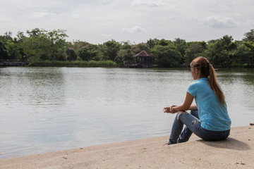 Naklejka na ściany i meble Young Asian woman sit near the Lake.