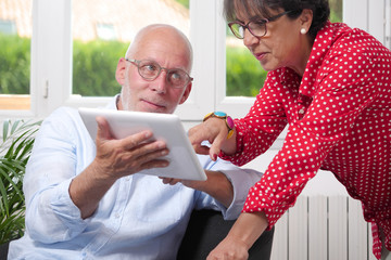Senior couple at home using digital tablet