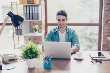 Happy handsome smiling man sitting at the table and chatting with his friends using laptop