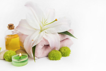 Spa still life setting with lily, towel,candle, oil bottle on white, copy space, wellness setting background