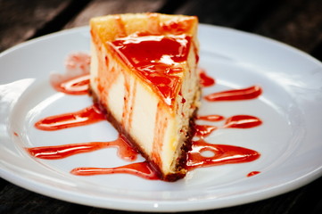 piece of orange cheese cake in the white plate on the brown wooden background