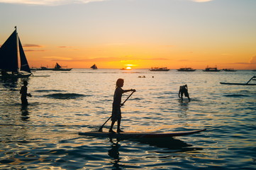 Beautiful colorful sunset over fishing boats and people in water