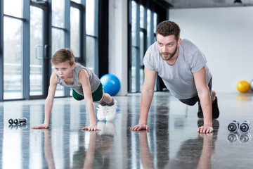 Man and boy doing push ups at fitness center