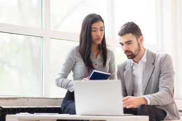Multi-ethnic team of managers wrapped up in work: they gathered together in modern office and preparing business presentation on laptop
