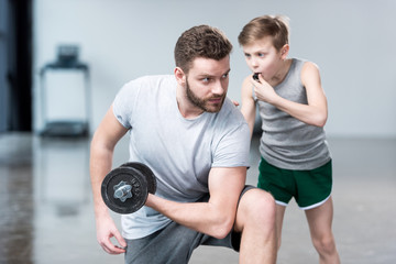 Boy coach training man exercising with dumbbell