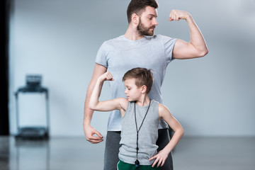 Boy with young man, his trainer or father showing muscles