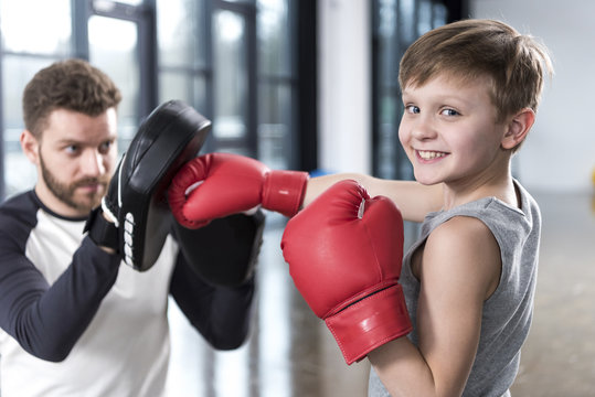 young boy boxer practicing punches with coach