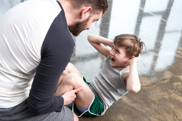 Boy doing sit-ups while trainer holding feet