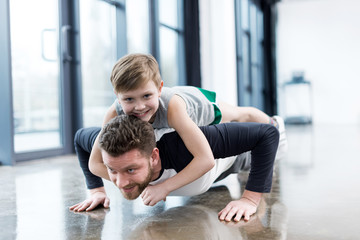 Man doing push ups with boy on his back