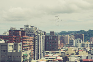 Image of residential area of New Taipei City, Taiwan. Sky is cloudy and birds are flying. Retro effect. 