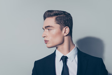 Close up of handsome mature guy with perfect hairstyle on pure light background. He is wearing suit and looking at his right