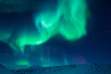 The polar Northern aurora borealis lights in Norway Svalbard in the mountains