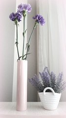  Purple carnation in vase pink and lavender bouquet in white basket on the table.