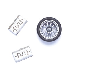 Wheel balance weight made from lead put beside plastic model of aluminum alloy wheel represent the wheel balance setting of vehicle.