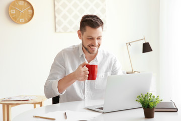Handsome young man working with laptop in office