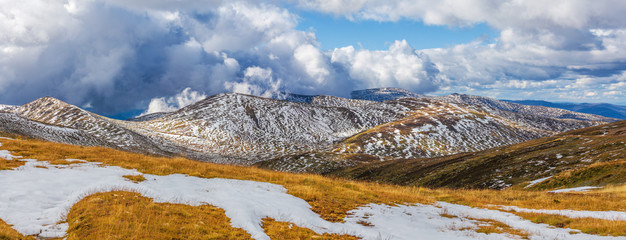 Beautiful panorama of snow covered Australian Alps and yellow grass. New South Wales, Australia