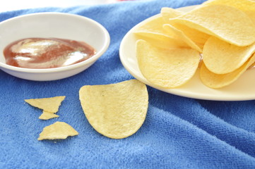 crispy and salt potato chips on dish dipping with ketchup