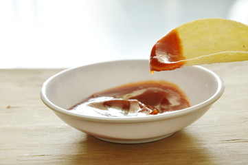 crispy and salt potato chips on dish dipping with ketchup