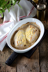 Chicken breast baked in sour cream sauce on an old wooden background. Rustic style.