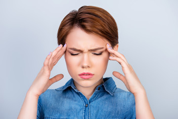 Cute young girl is suffering from strong headache. She is holding her head with hands