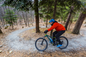 Fototapeta na wymiar Mountain biker riding on bike in early spring mountains forest landscape. Man cycling MTB enduro flow trail track. Outdoor sport activity.