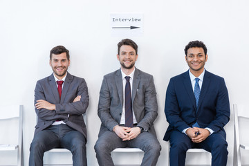 businessmen in suits sitting on chairs at white waiting room. business meeting