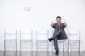 businessman showing thumbs up and waiting for interview in office, business concept