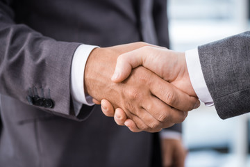 cropped view of businessmen shaking hands in office, business meeting concept