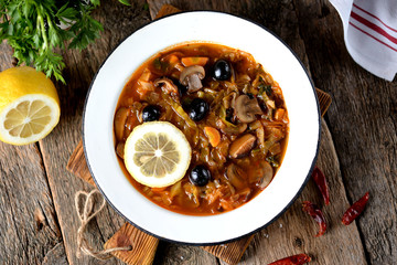 Traditional Russian soup solyanka made from cabbage, fresh and dried mushrooms with olives, lemon and capers.
