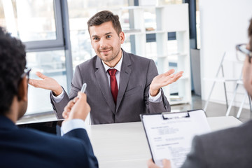 smiling businessman gesturing during job interview, business concept