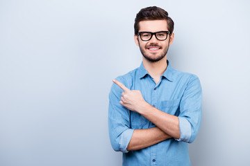 Cheerful handsome young man i glasses is showing direction and pointing with his finger