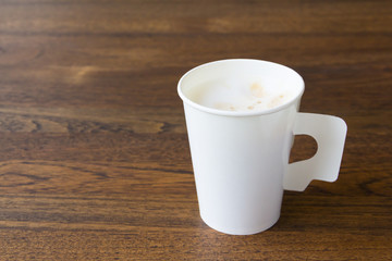 latte coffee in white paper cup on wooden table