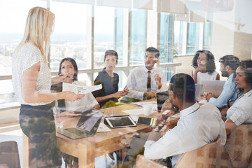 Businesswoman Leads Meeting Around Table Shot Through Door