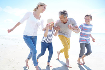 Obraz premium Happy family of four walking on sandy beach