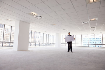 Male Architect In Modern Empty Office Looking At Plans