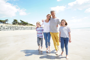 Happy family of four walking on sandy beach