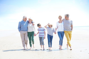 Family, parents, grandparents and grandkids walking on the beach