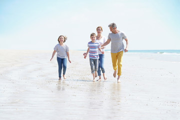 Fototapeta na wymiar Happy family of four walking on sandy beach