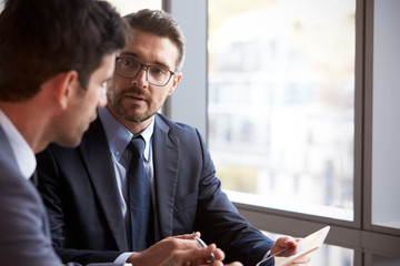 Two Businessmen Using Digital Tablet In Office Meeting