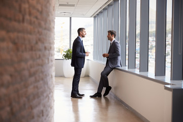 Two Businessmen Having Informal Meeting In Office Corridor